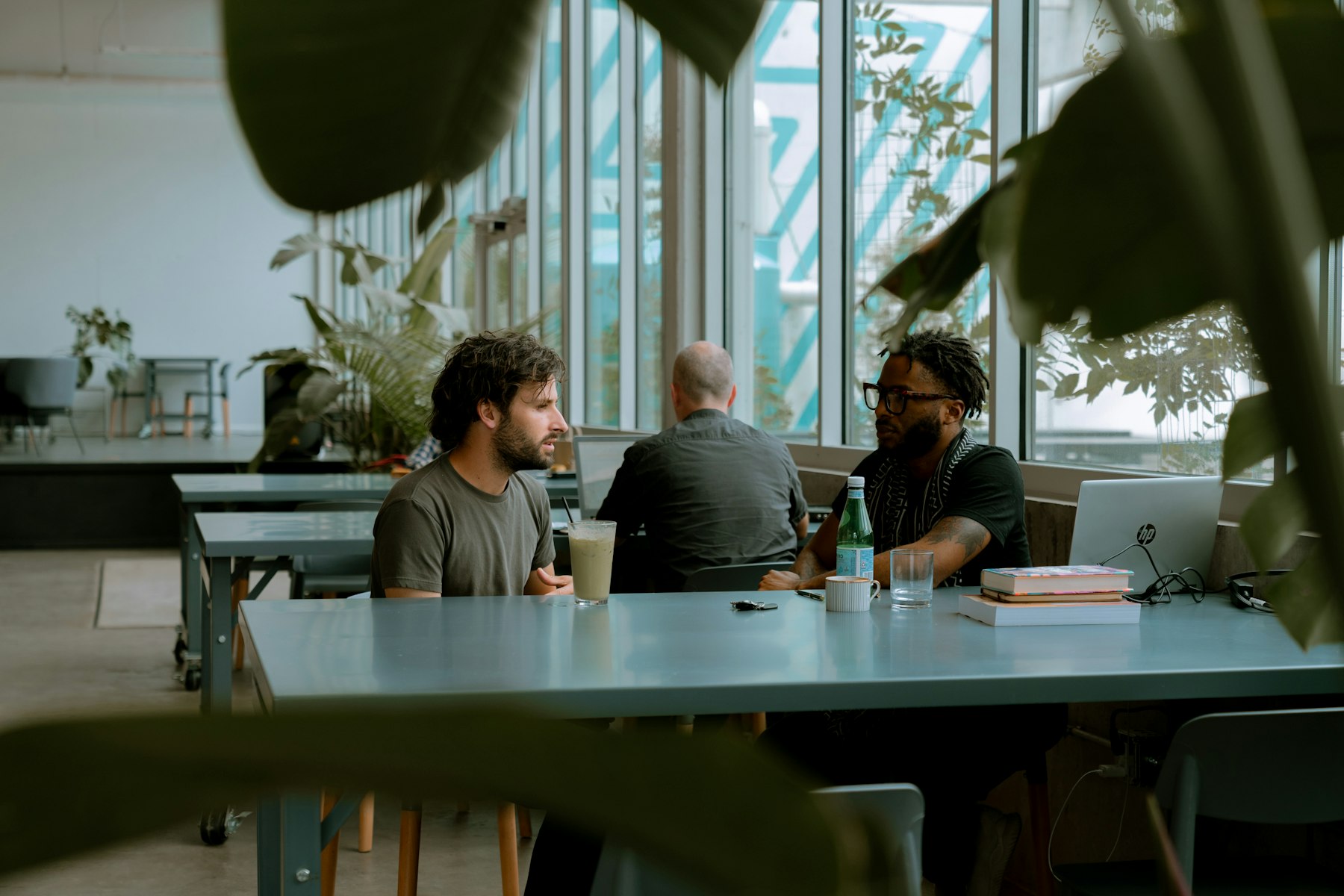 A team talking around a table in a plant-filled coworking space.